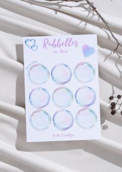 Rubbellos-Karte mit neun schimmernden Rubbelkreisen auf weißem Hintergrund, personalisiert mit Namen „Tobias“ – fotografiert auf Stoff mit Trockenblumen und Zweigen